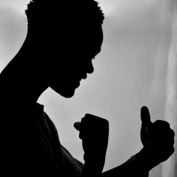 Silhouette of a man in a calm, powerful stance against a vibrant background.